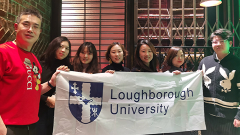 A group of seven people holding a Loughborough University banner